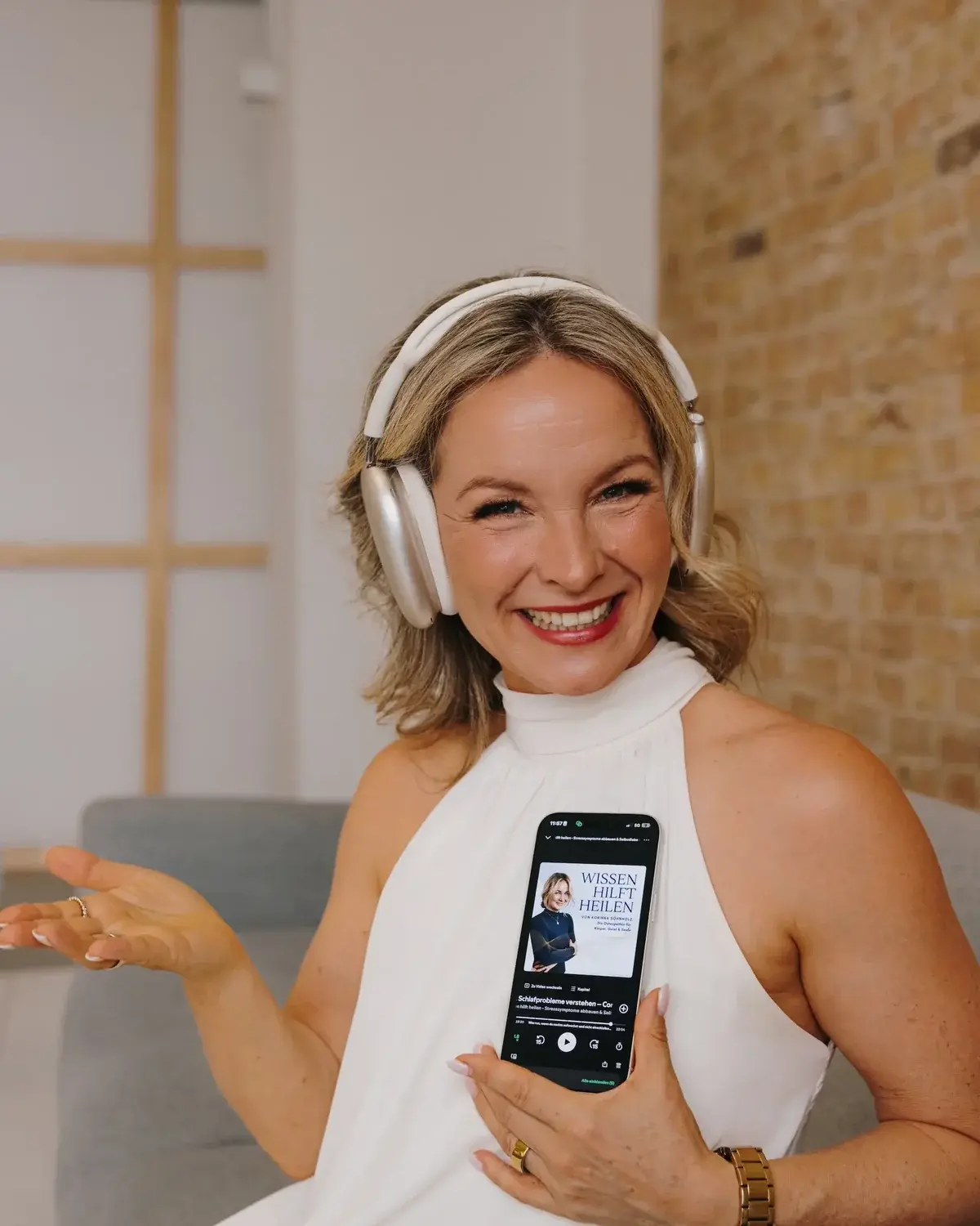 Korinna Söhnholz mit Kopfhörern, auf dem Handy läuft ihr Podcast